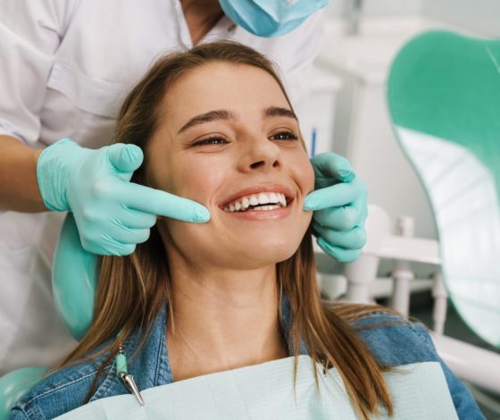 european-young-woman-smiling-while-looking-at-mirror-in-dental-clinic